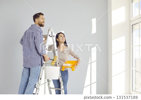 Smiling married young couple doing renovations at home Smiling married young couple doing renovations at home 131537189