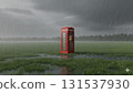 red telephone booth is surrounded by a vast field with heavy rain pouring and forming puddles. Dark storm clouds loom overhead as dusk approaches 131537930
