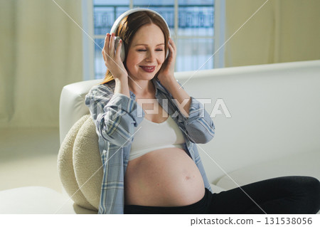 Pregnancy motherhood. Pregnant woman listening music for mother and unborn baby at home. Girl in headphones enjoying pregnancy listen music for relax healthy zen calm peace wellness, Maternity concept Pregnancy motherhood. Pregnant woman listening music for mother and unborn baby at home. Girl in headphones enjoying pregnancy listen music for relax healthy zen calm peace wellness, Maternity concept 131538056