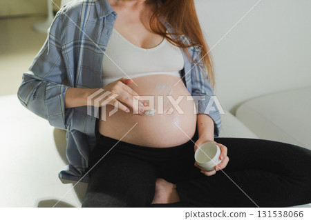Pregnancy motherhood. Pregnant woman applying cream lotion on big belly takes care of her skin. Cosmetic product for prevention stretch mark. Girl enjoying pregnancy at home. Maternity health concept Pregnancy motherhood. Pregnant woman applying cream lotion on big belly takes care of her skin. Cosmetic product for prevention stretch mark. Girl enjoying pregnancy at home. Maternity health concept 131538066