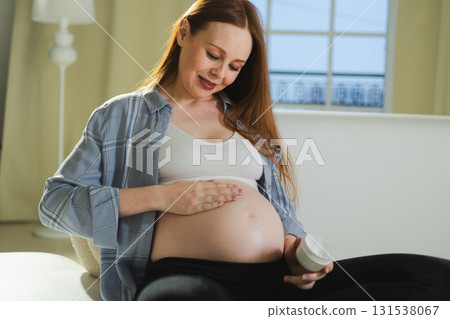 Pregnancy motherhood. Pregnant woman applying cream lotion on big belly takes care of her skin. Cosmetic product for prevention stretch mark. Girl enjoying pregnancy at home. Maternity health concept Pregnancy motherhood. Pregnant woman applying cream lotion on big belly takes care of her skin. Cosmetic product for prevention stretch mark. Girl enjoying pregnancy at home. Maternity health concept 131538067