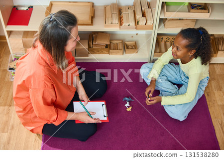 Psychologist and girl sitting on floor during therapy session 131538280