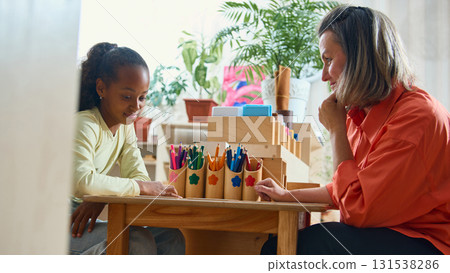 Teacher guiding child in creative classroom activity for psychological support 131538286