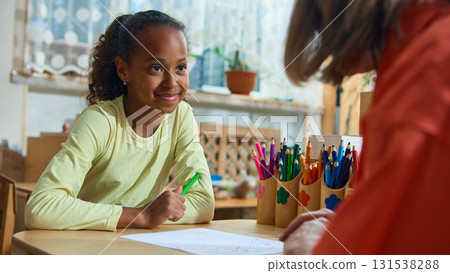 Young girl smiling at therapist during child counseling and creative activity session Young girl smiling at therapist during child counseling and creative activity session 131538288