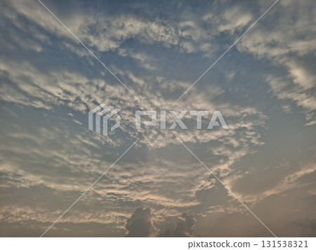Dramatic, wispy clouds streak across a vast sky, illuminated by soft, golden sunlight, creating a serene and ethereal Dramatic, wispy clouds streak across a vast sky, illuminated by soft, golden sunlight, creating a serene and ethereal 131538321