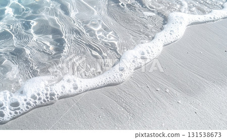 Close-up of gentle ocean waves lapping on a sandy beach with fine white sand and clear seawater creating a calming coastal scene du daytime 131538673