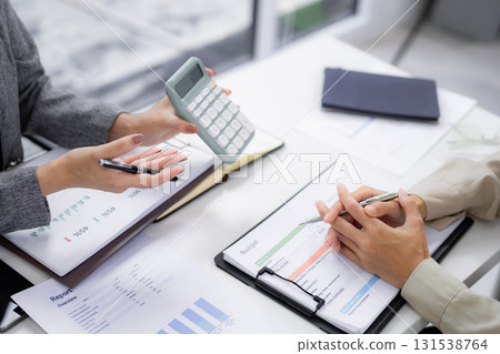 Business professionals review financial reports calculate budgets discuss investment strategy office meeting analyzing data Business professionals review financial reports calculate budgets discuss investment strategy office meeting analyzing data 131538764