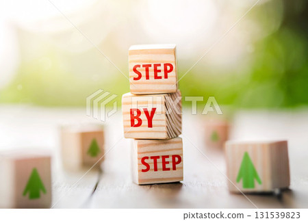 The word step by step on wooden cubes. Achievement or progress in business career. The word step by step on wooden cubes. Achievement or progress in business career. 131539823