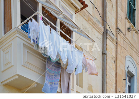 Malta balcony with hanging laundry on limestone facade in Valletta old town 131541027