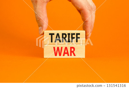Trade tariff war symbol. Concept word Tariff war on beautiful wooden blocks. Beautiful orange paper background. Businessman's hand. Business trade tariff wars concept. Copy space. 131541316