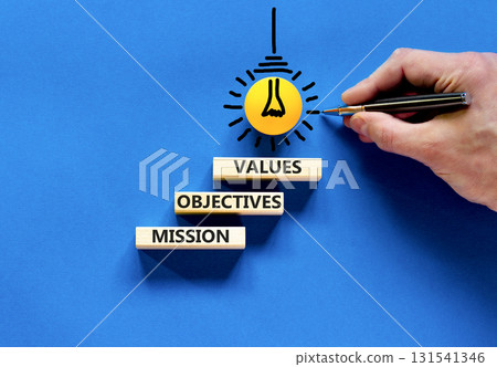 Mission objectives values symbol. Concept words Mission Objectives Values on beautiful blocks. Beautiful blue background. Businessman hand. Business mission objectives values concept. Copy space. 131541346