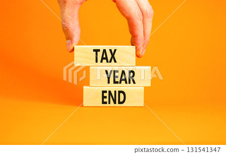 Tax year end symbol. Concept words Tax year end on beautiful wooden blocks. Beautiful orange background. Businessman hand. Business tax year end concept. Copy space. 131541347