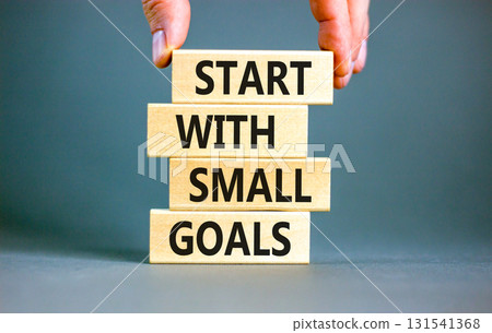 Start with small goals symbol. Concept words phrase Start with small goals on beautiful wooden blocks. Beautiful grey background. Businessman's hand. Business Start with small goals concept Copy space 131541368