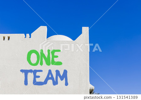 One team symbol. Concept word One team on beautiful white wall. Beautiful blue sky background. Business one team concept. Copy space. 131541389
