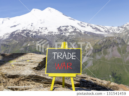 Trade war symbol. Concept word Trade war on beautiful black blackboard. Beautiful stone mountain Elbrus blue sky background. Black blackboard. Business trade war concept. Copy space. 131541459