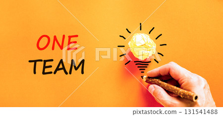 One team symbol. Concept word One team on beautiful orange paper. Businessman's hand. Light bulb icon. Beautiful orange paper background. Business one team concept. Copy space. 131541488