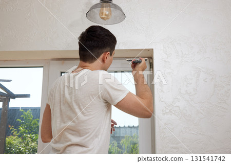 Caucasian plasterer man with a spatula applying finishing putty on a window opening 131541742