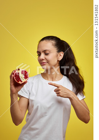 Beautiful happy woman holding pomegranate on yellow background Beautiful happy woman holding pomegranate on yellow background 131541802