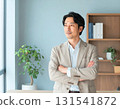 Portrait of a middle-aged man standing indoors with his arms crossed, in a business casual style 131541872