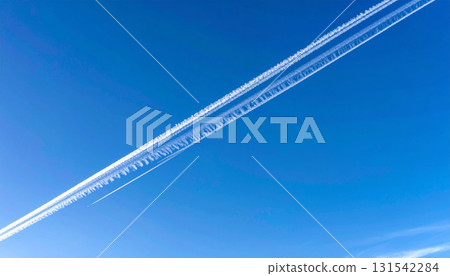 A sharp contrail cuts straight across the clear blue sky 131542284