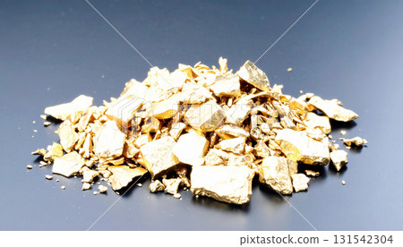 A pile of raw gold nuggets on a dark background 131542304