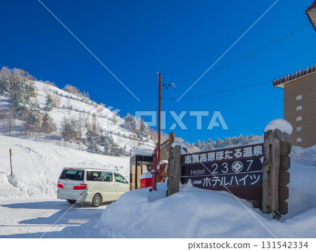 A sign and snowy road leading to a hot spring resort at the foot of a ski resort on a clear day (Yamanouchi Town, Nagano Prefecture) A sign and snowy road leading to a hot spring resort at the foot of a ski resort on a clear day (Yamanouchi Town, Nagano Prefecture) 131542334