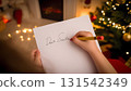 Childrens hands with a pen writing a dear Santa letter among Christmas decoration in kids room, close-up 131542349