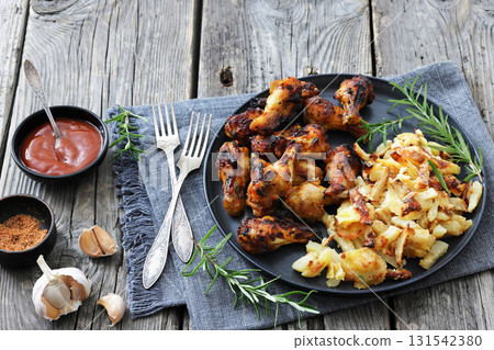 bbq chicken wings with fried potatoes on plate 131542380