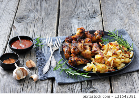 bbq chicken wings with fried potatoes on plate 131542381