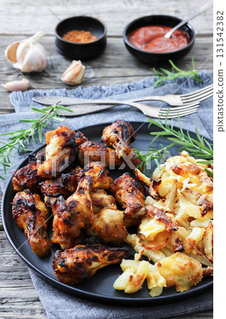 bbq chicken wings with fried potatoes on plate bbq chicken wings with fried potatoes on plate 131542382