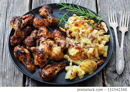 bbq chicken wings with fried potatoes on plate 131542388