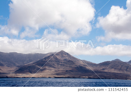 A wide, choppy ocean and a brown, bald mountain in the distance. On the sea of Fuerteventura in the Canary Islands. 131542455