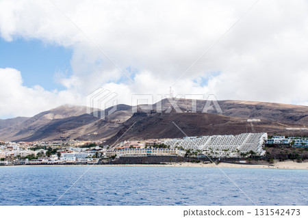 從富埃特文圖拉島的海上望去,海岸邊有白色的沙灘、度假酒店和棕色的禿山 從富埃特文圖拉島的海上望去,海岸邊有白色的沙灘、度假酒店和棕色的禿山 131542473