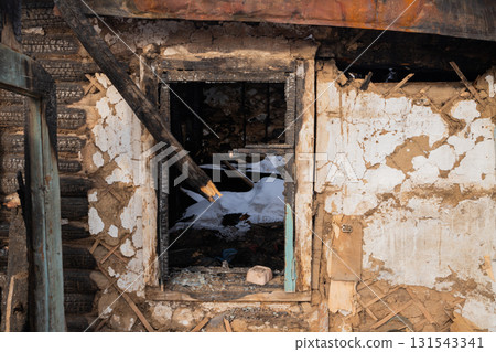 A charred window frame reveals the inside of a burned building, showcasing debris and remnants of a recent fire in an abandoned location. A charred window frame reveals the inside of a burned building, showcasing debris and remnants of a recent fire in an abandoned location. 131543341