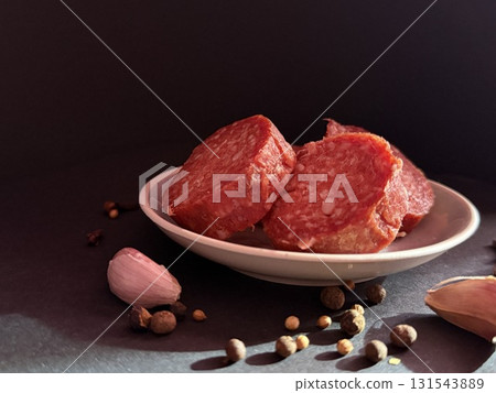 Slices of salami with garlic and pepper. Salami slices with shallots and peppercorns. Slices of salami with garlic and pepper. Salami slices with shallots and peppercorns. 131543889