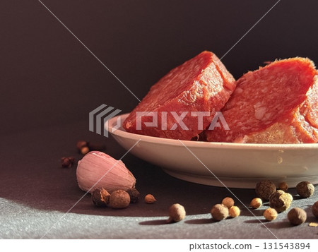 Slices of salami with garlic and pepper. Salami slices with shallots and peppercorns. Slices of salami with garlic and pepper. Salami slices with shallots and peppercorns. 131543894