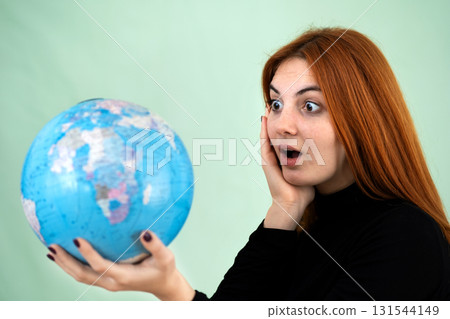 Portrait of a sad worried young woman holding geographic globe of the world in her hands. Travel destination and planet protection concept. 131544149