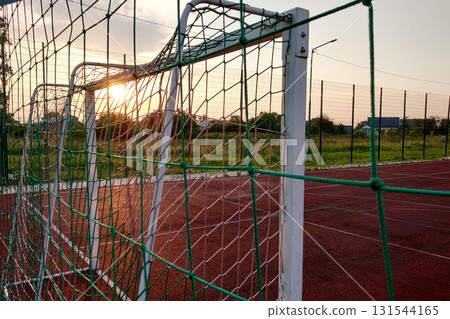Outdoors mini football and basketball court with ball gate and basket surrounded with high protective fence. 131544165