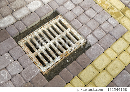 Old rusted metal gutter for rain water on the stone paved sidewalk. 131544168