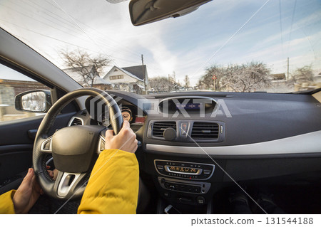 Modern car interior with driver female hands on steering wheel, winter snowy landscape outside. Safe driving concept. Modern car interior with driver female hands on steering wheel, winter snowy landscape outside. Safe driving concept. 131544188