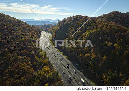 I-40 freeway road leading to Asheville in North Carolina thru Appalachian mountains with yellow fall forest and fast moving trucks and cars. Concept of high speed interstate transportation I-40 freeway road leading to Asheville in North Carolina thru Appalachian mountains with yellow fall forest and fast moving trucks and cars. Concept of high speed interstate transportation 131544234