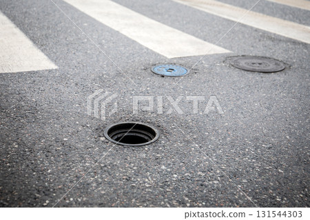 Manhole Covers and Street Asphalt with Zebra Crosswalk in Urban Area 131544303