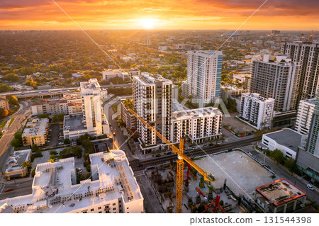 Housing growth in the USA. New skyscraper construction in Miami, Florida at sunset. Developing residence in American urban area. Industrial tower lifting cranes at building site Housing growth in the USA. New skyscraper construction in Miami, Florida at sunset. Developing residence in American urban area. Industrial tower lifting cranes at building site 131544398
