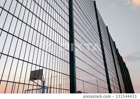 High wire mesh fence in restricted area on blue sky background. 131544413