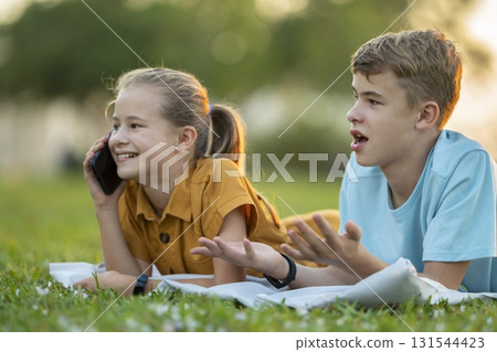 Happy young girl chatting on mobile phone ignoring her bored friend. Teenager friends having hard time communicating with each other. Friendship problems concept 131544423