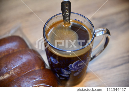 Golden honey dripping from spoon into brown ginger tea on wooden table Golden honey dripping from spoon into brown ginger tea on wooden table 131544437