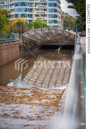 Flooded underpass, underground street in urban area after heavy rain, reflecting metal structure and autumn debris. Concept of urban flooding, climate crisis, and extreme weather consequences 131544755