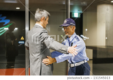 Security guard conducting a body check 131545013