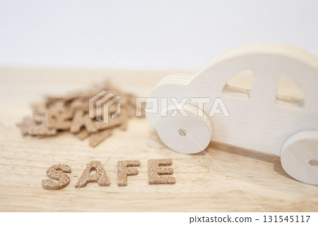 一輛木製玩具車和“SAFE”字樣。道路安全和安全駕駛的圖片。 131545117