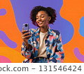 Smiling young woman with curly hair using a smartphone, enjoying online communication against a vibrant abstract background, radiating happiness in the digital age 131546424